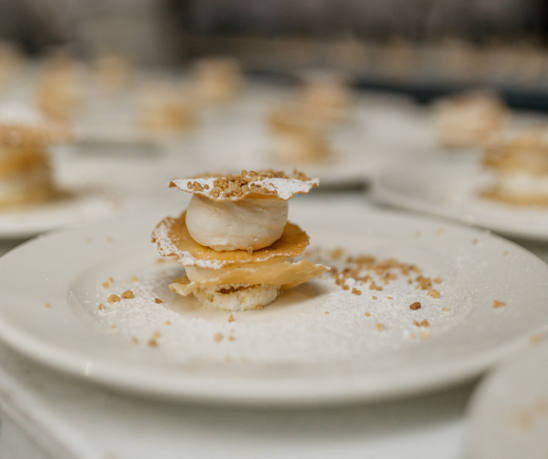 Postre de hojaldre y crema espolvoreado sobre plato blanco.